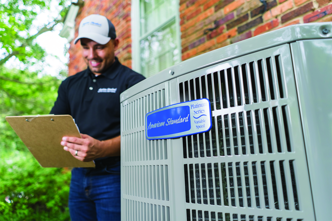 A technician checking on an outdoor air conditioning unit