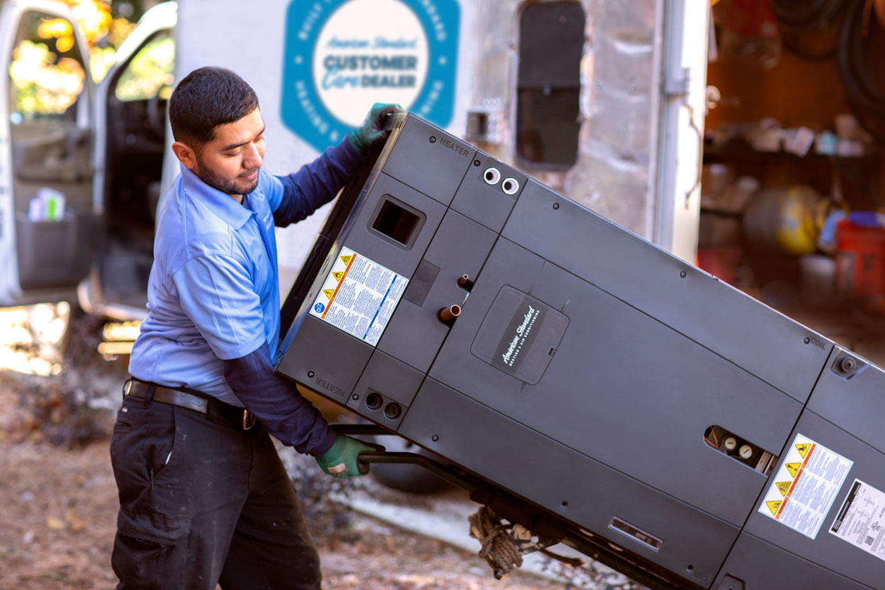 Technician pushing an American Standard unit on a handcart 