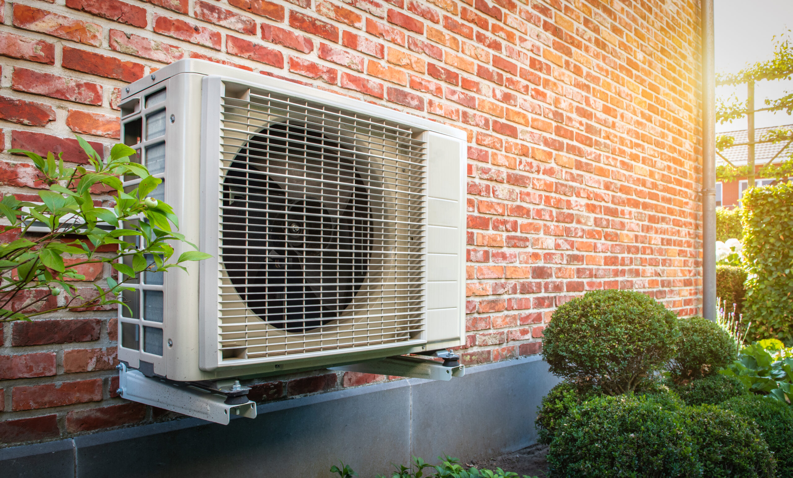Heat pump mounted on a brick wall of a residence